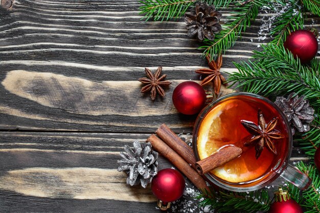 Vin chaud de Noël avec des branches de cannelle, d'anis et de sapin avec des décorations sur fond en bois avec espace de copie. vue de dessus. boisson d'hiver