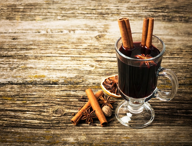 Vin chaud de Noël dans une tasse en verre sur une table en bois.