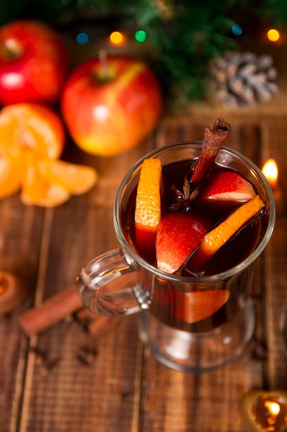 Vin chaud de Noël avec des fruits et des épices sur une table en bois