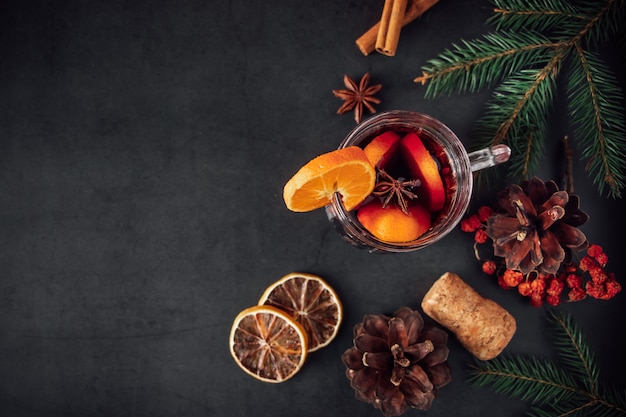 Vin chaud de Noël traditionnel. Boisson chaude aux épices dans une tasse en verre sur fond sombre.