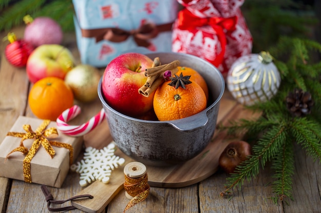 Vin chaud de Noël vin chaud aux épices et fruits sur une table en bois. Boisson chaude traditionnelle pour Noël. Vin chaud aux agrumes, pommes et épices dans une casserole.