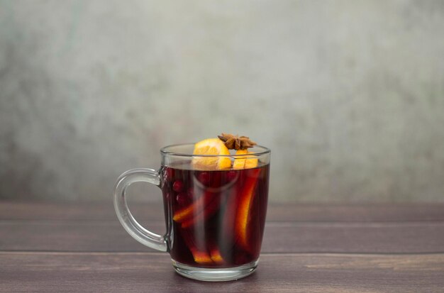 Vin chaud à l'orange dans un verre sur fond gris et marron