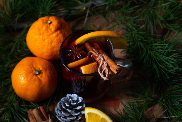 Vin chaud parfumé, épices et mandarines sur un arbre de Noël