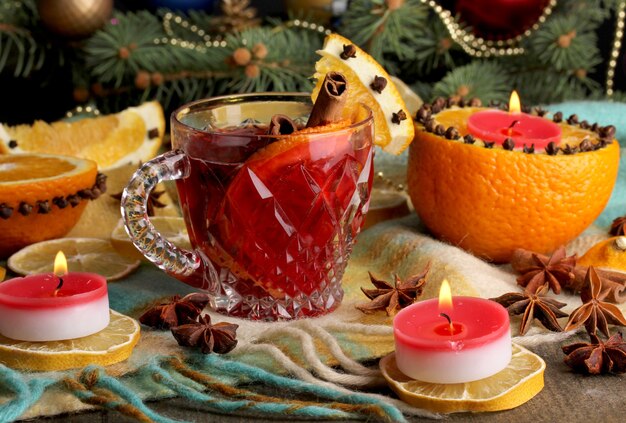 Vin chaud parfumé en verre avec des épices et des oranges autour sur une table en bois