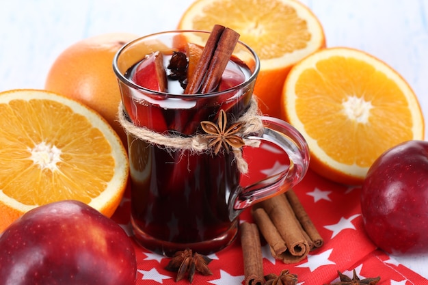 Vin chaud parfumé en verre sur serviette et table en bois close-up