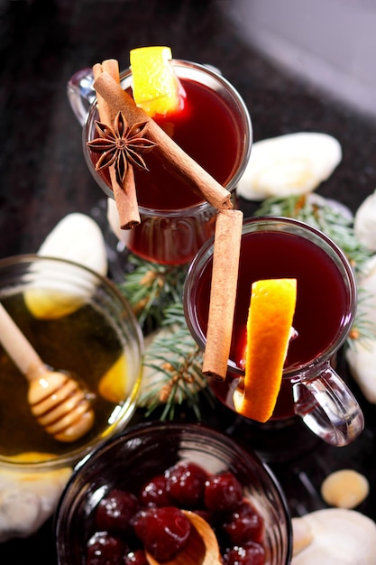 Vin chaud rouge miel d'abeille tranches d'oranges et d'épices sur un fond sombre décoration de Noël avec des branches d'épinette libre