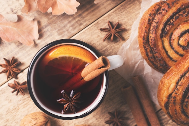 Vin chaud traditionnel en tasse avec pâtisserie et épices sur bois