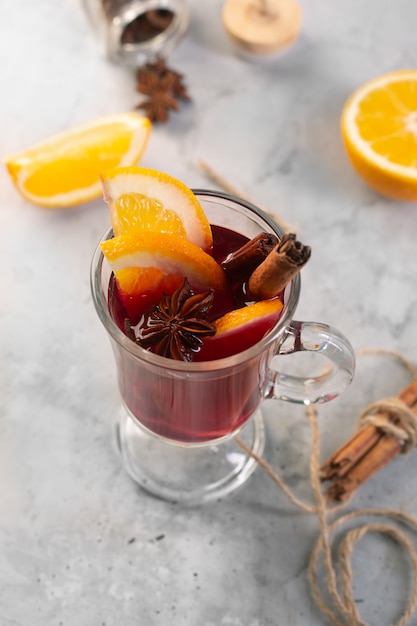 Vin chaud avec tranche d'orange et d'épices sur fond de béton gris