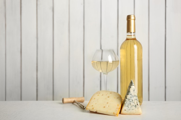 Vin et fromage sur fond de mur en bois