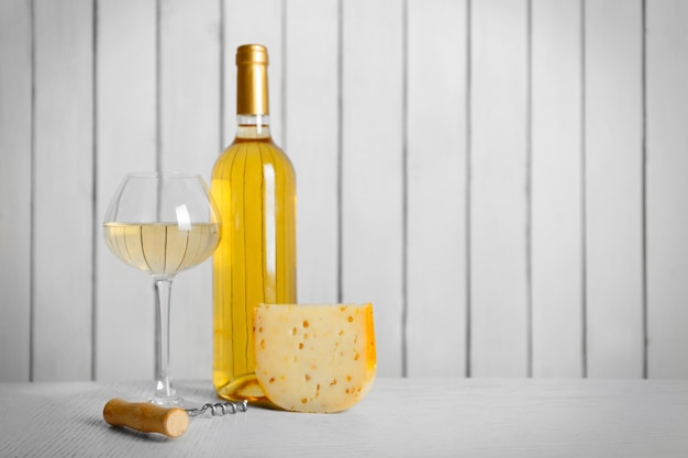 Vin et fromage sur fond de mur en bois