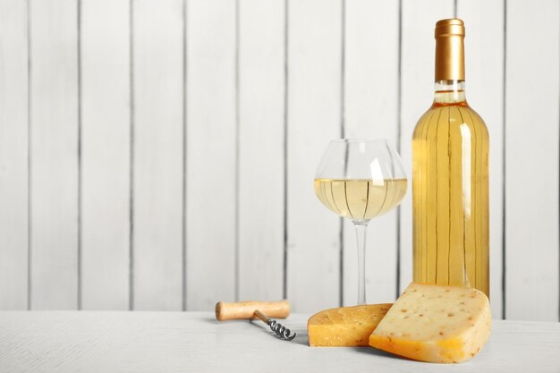 Vin et fromage sur fond de mur en bois