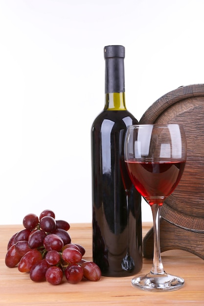 Vin en gobelet et en bouteille raisins et tonneau sur table en bois sur fond blanc