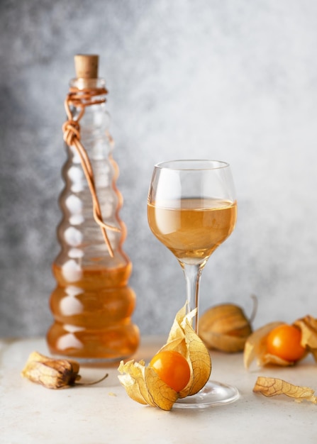 Vin ou liqueur maison de fruits de physalis dans un petit verre avec des fruits frais mûrs