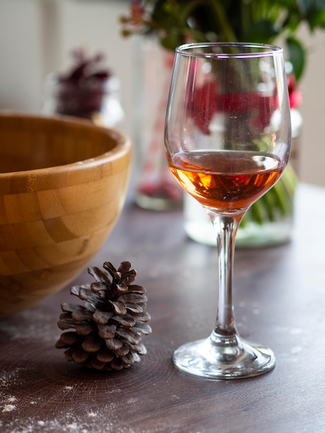 Photo vin de nature morte verticale dans un verre sur une table en bois vintage. boisson de réchauffement de noël ou d'hiver avec des pommes de pin autour.