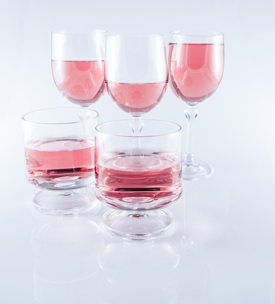 Vin rose dans des verres à pied sur fond blanc