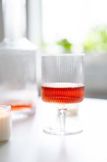 Vin rosé dans des verres à vin côtelés à la mode et carafe sur table blanche