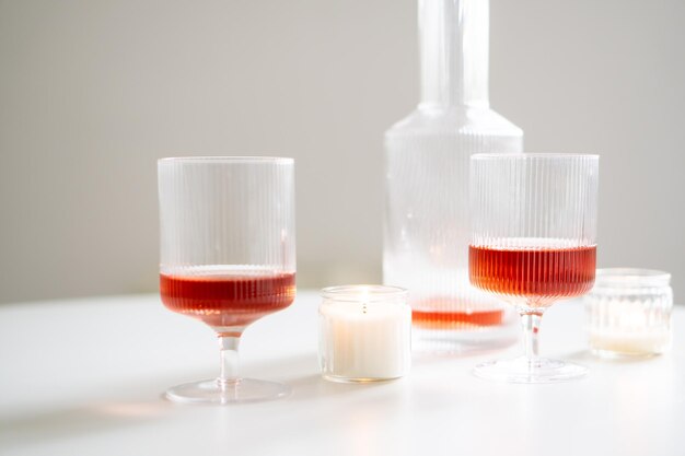 Vin rosé dans des verres à vin côtelés à la mode et carafe sur table blanche