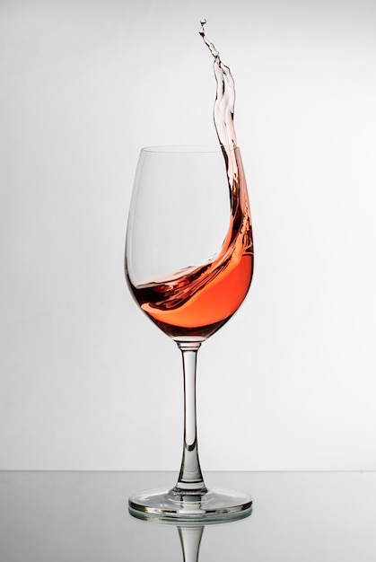 Vin rose éclaboussant le côté d'un verre à vin