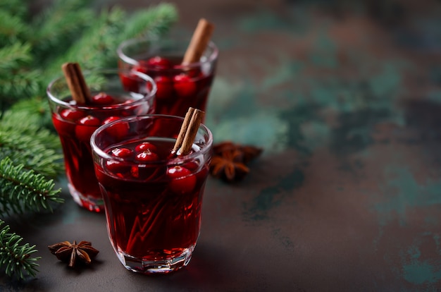 Vin rouge chaud aux canneberges. Concept de vacances décoré de branches de sapin et d'épices.