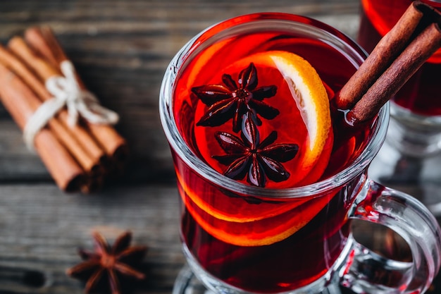 Vin rouge chaud aux épices et orange en verre sur un fond rustique en bois Boisson de Noël maison