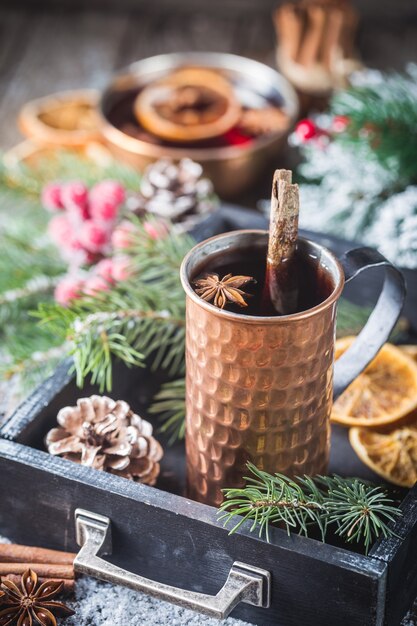 Vin rouge chaud de Noël aux épices et fruits sur une table rustique en bois. Boisson chaude traditionnelle au moment de Noël