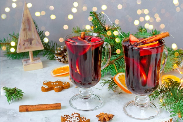 Vin rouge chaud de Noël avec des épices et des oranges sur une table rustique en bois. Boissons traditionnelles du Nouvel An.