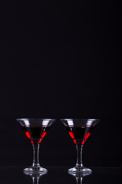 Vin rouge dans deux verres de martini sur fond noir