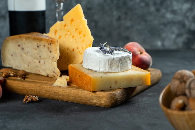 Vin rouge et fromage. Différents types de fromage avec noix, lavande et pêche aux figues sur une planche à découper. Dîner romantique. Copiez l'espace pour la conception. Fond sombre. Flou artistique