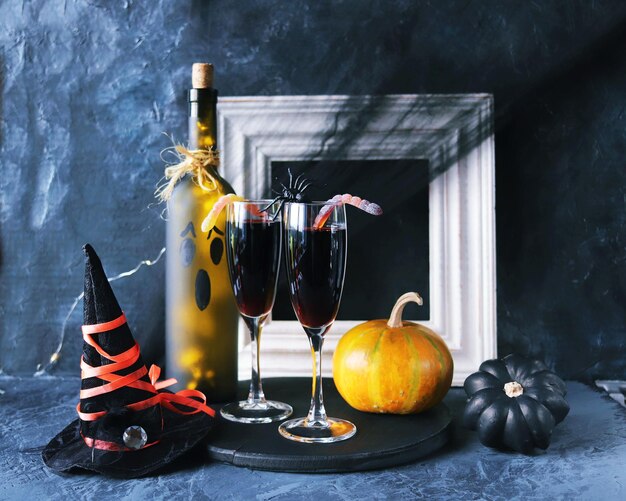 Photo vin rouge d'halloween dans des verres et une bouteille de décorations mystiques de citrouilles sur fond noir