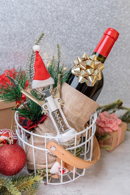 Vin rouge de Noël et ouvre-vin avec décoration de bonnet de noel sur fond de table.