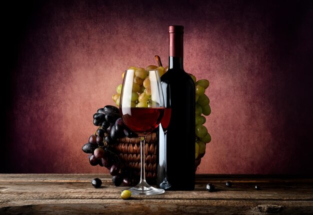 Photo vin rouge avec panier de raisin sur table