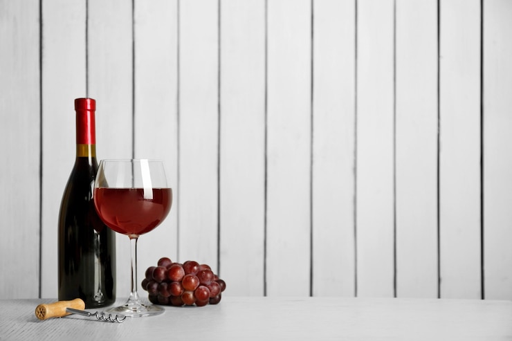 Photo vin rouge avec raisin sur fond de mur en bois
