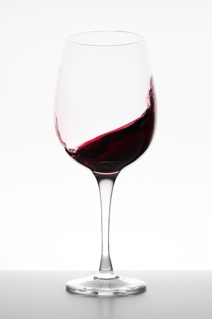 Vin rouge tourbillonnant dans le verre sur fond blanc