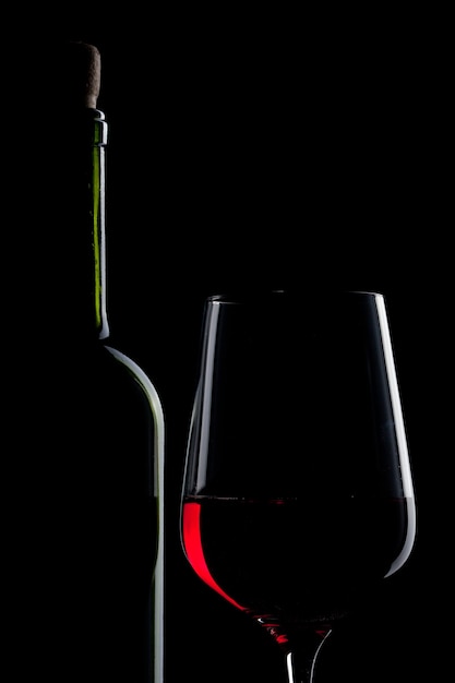 Vin rouge en verre et bouteille isolé sur fond noir