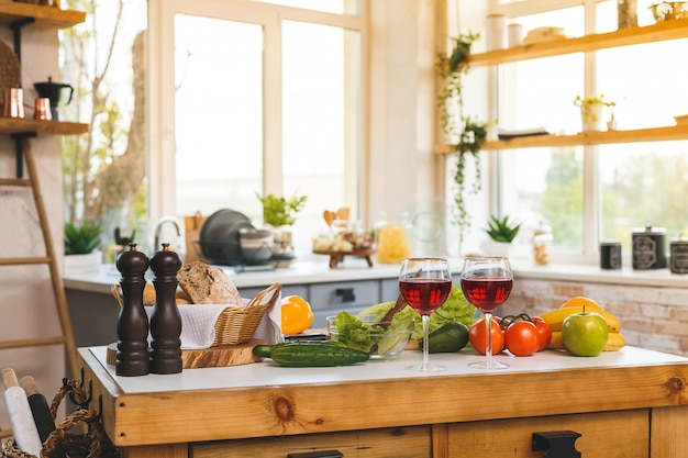 Vin rouge, verres et aliments sains sur une table dans une cuisine moderne. Intérieur de la maison.