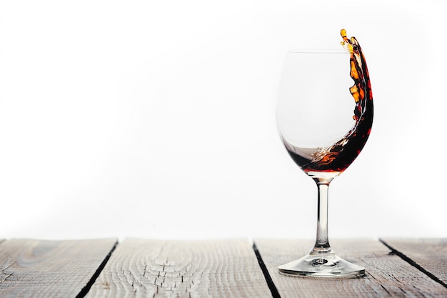 Vin rouge versé dans un verre sur fond blanc