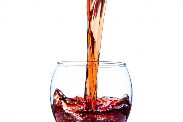 Vin rouge versé dans un verre à vin isolé sur fond blanc