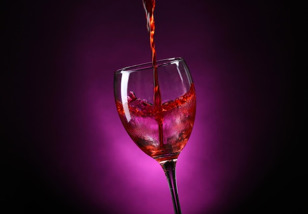 Vin versé dans un verre sur fond violet foncé