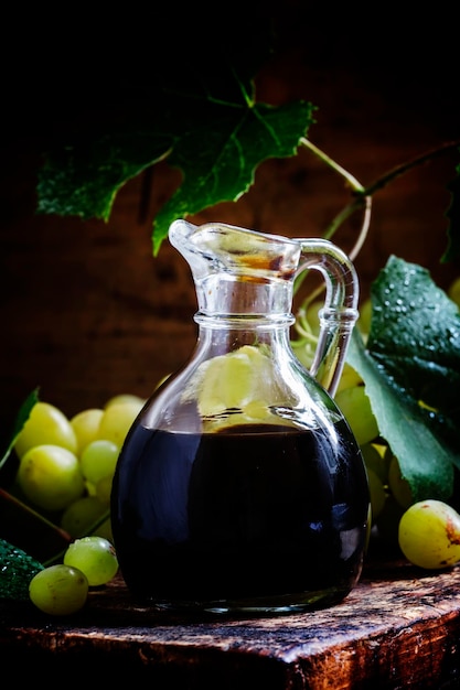 Vinaigre balsamique dans une verseuse en verre fond en bois vintage style rustique mise au point sélective