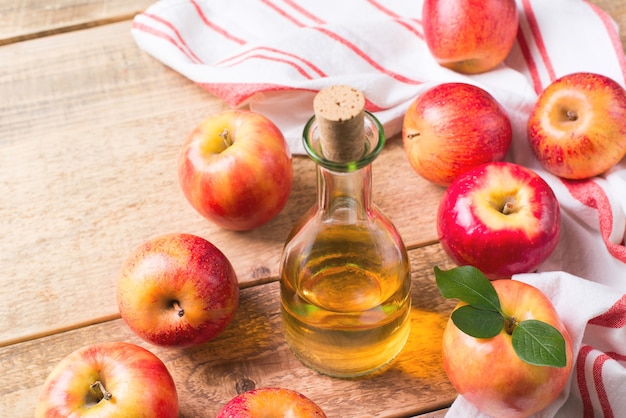 Vinaigre de cidre de pomme en bouteille avec pomme sur bois