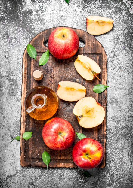 Photo vinaigre de cidre de pomme avec des pommes fraîches sur une planche à découper