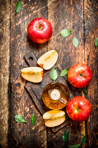 Vinaigre de cidre de pomme, pommes rouges sur table en bois.