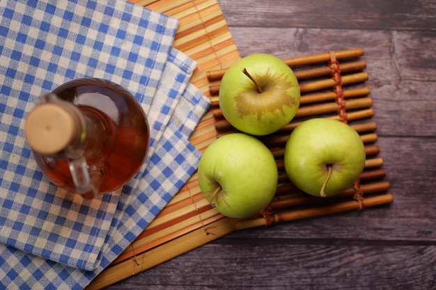 Vinaigre de pomme en bouteille en verre avec pomme verte fraîche sur table