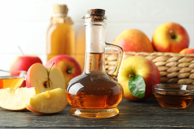 Vinaigre de pomme fait maison et ingrédients sur table en bois