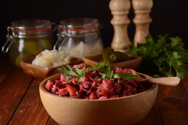 Vinaigrette ou vinaigrette. Salade rouge russe traditionnelle avec légumes cuits et marinés, pois, betteraves rouges, dans un bol en bois sur fond rustique.