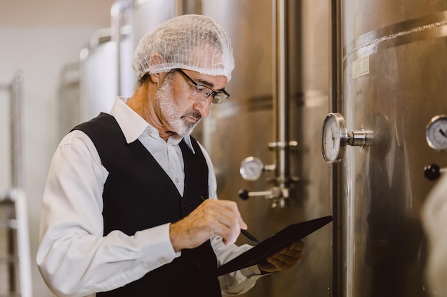 Photo viniculteur professionnel travaillant dans une grande usine de vin moderne de qualité dans l'industrie des boissons alcoolisées