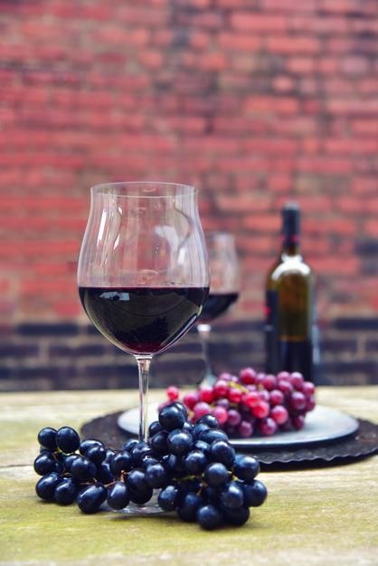 Des vins avec des raisins servis sur la table contre un mur de briques