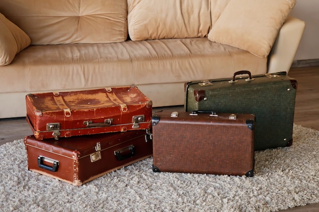 Vintage vieilles valises en cuir classiques obsolètes à l'intérieur d'une pièce lumineuse par canapé. Arrière-plan avec des valises de différents modèles et couleurs. Asseyons-nous sur le chemin ! Concept Bagage pour le voyage. Espace de copie