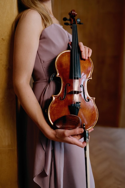 Violon dans des mains féminines. Musicien femme élégante tenant un instrument de musique classique. Photo recadrée