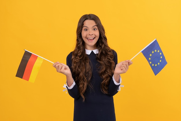 Visa touristique dans le pays schengen. kid girl voyage et étudie à l'étranger. vacances en allemagne. éducation dans une école étrangère. fan de football. enfant surpris tenant l'union européenne et le drapeau allemand.